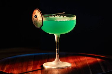 Ahşap tepside canlı renkte, sert dramatik ışıklandırmalı klasik yeşil içecek.