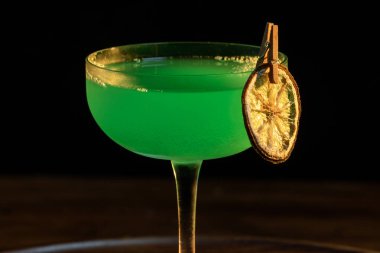 Ahşap tepside canlı renkte, sert dramatik ışıklandırmalı klasik yeşil içecek.