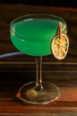 Ahşap tepside canlı renkte, sert dramatik ışıklandırmalı klasik yeşil içecek.