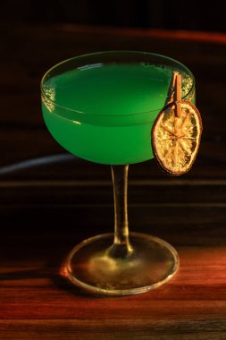 Ahşap tepside canlı renkte, sert dramatik ışıklandırmalı klasik yeşil içecek.