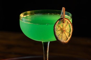 Ahşap tepside canlı renkte, sert dramatik ışıklandırmalı klasik yeşil içecek.