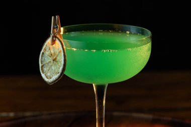 Ahşap tepside canlı renkte, sert dramatik ışıklandırmalı klasik yeşil içecek.