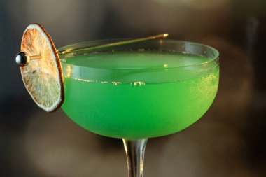 Ahşap tepside canlı renkte, sert dramatik ışıklandırmalı klasik yeşil içecek.