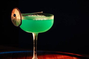 Ahşap tepside canlı renkte, sert dramatik ışıklandırmalı klasik yeşil içecek.