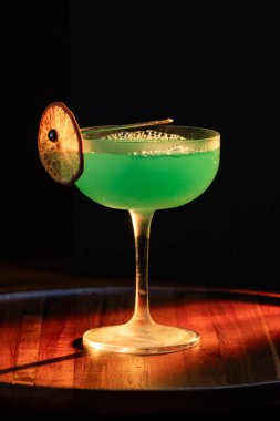 Ahşap tepside canlı renkte, sert dramatik ışıklandırmalı klasik yeşil içecek.