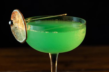 Ahşap tepside canlı renkte, sert dramatik ışıklandırmalı klasik yeşil içecek.