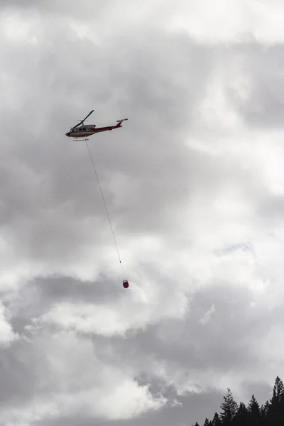 Helikopter pemadam kebakaran terbang di atas awan putih — Stok Foto