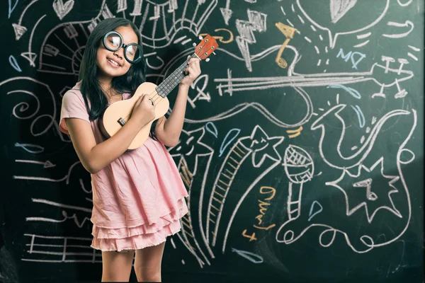 Petite fille intelligente souriant devant un tableau noir — Photo