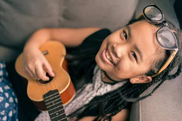 Glada leende flicka lära sig spela musik — Stockfoto