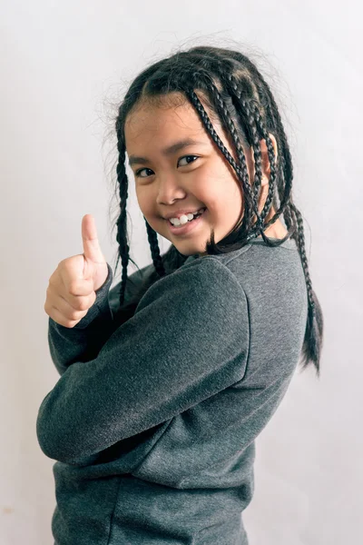 Söt liten flicka, dreadlocks frisyr med tummen upp mot en vit bakgrund — Stockfoto