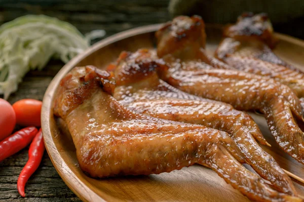 Asas de frango grelhadas em placa de madeira — Fotografia de Stock