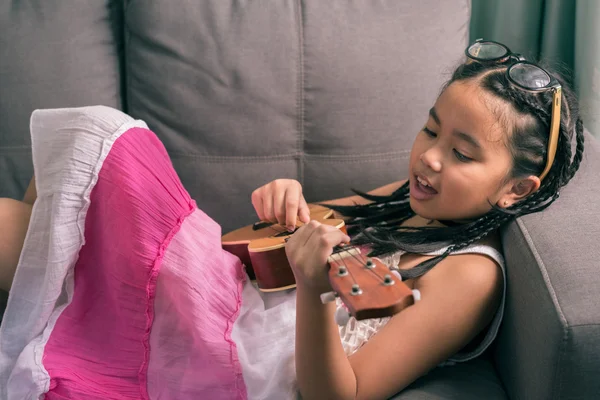 Felice ragazza sorridente imparare a giocare l'Ukulele — Foto Stock