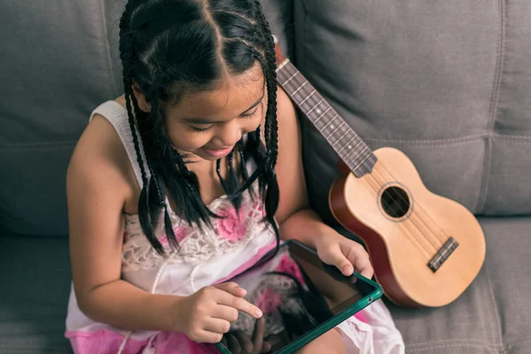 Petite fille mignonne, jouant avec l'ordinateur à la maison couché sur le canapé — Photo