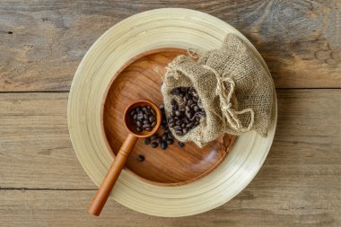 Tahta bir arka planda poşette kahve çekirdekleri