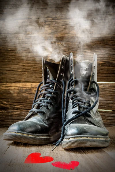 Paar alte Stiefel, die vor Liebe auf Holz dampfen — Stockfoto