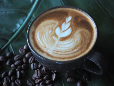 Güzel Latte sanatıyla birlikte bir fincan kahve. Kahve fincanı ve ahşap masa üzerinde kahve sanatı..