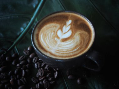 Güzel Latte sanatıyla birlikte bir fincan kahve. Kahve fincanı ve ahşap masa üzerinde kahve sanatı..