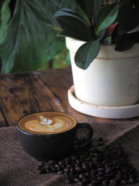 Güzel Latte sanatıyla birlikte bir fincan kahve. Kahve fincanı ve ahşap masa üzerinde kahve sanatı..