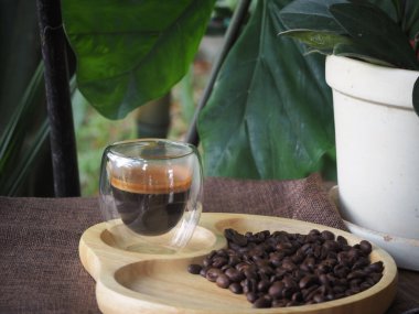 Masada bir fincan espresso. Kokteyl ya da kahve için cam deney şişesi. Bir bardak espresso iç. Beyaz arka planda çift duvarlı sıcak kahve..