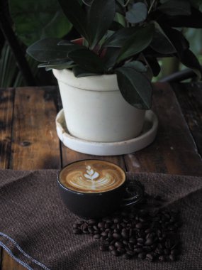 Güzel Latte sanatıyla birlikte bir fincan kahve. Kahve fincanı ve ahşap masa üzerinde kahve sanatı..