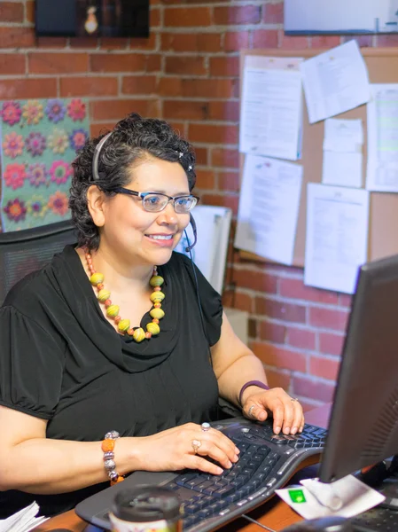 Mulher hispânica de meia-idade no escritório usando Headph — Fotografia de Stock