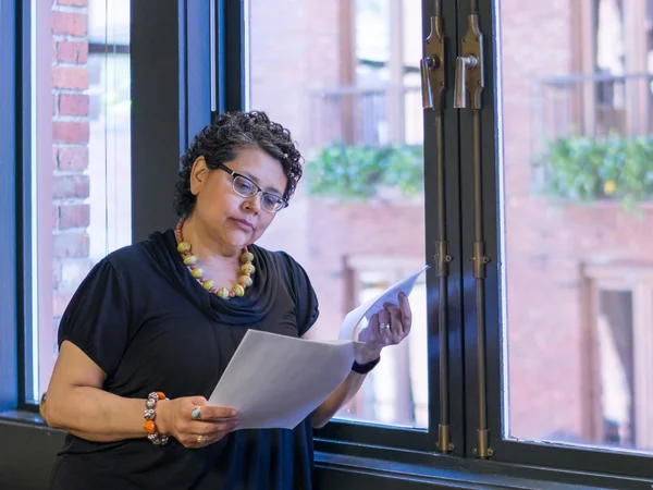 Hispanic Female Standing By Window Holding Papers In Office Setting — Stock Photo, Image