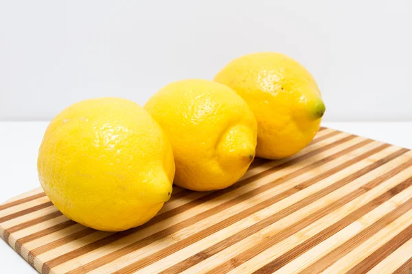 Three lemons on cutting board — Stock Photo, Image