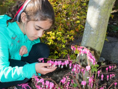 Kız çiçek gözlemleyerek bahçede zaman zevk