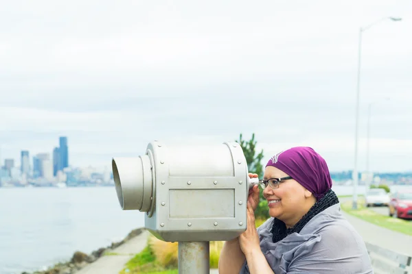 Mujer de mediana edad usando un telescopio público — Foto de Stock