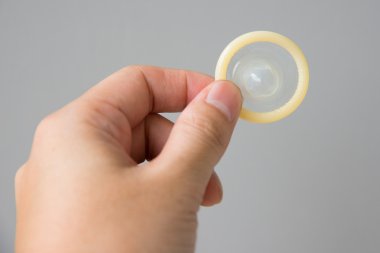 Prezervatif biri içinde el gri arka plan üzerinde