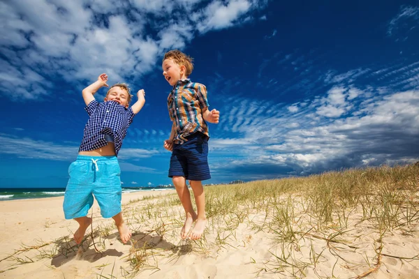 Junge glückliche Jungen haben Spaß am tropischen Strand, springen in die — Stockfoto