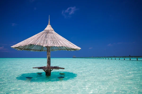 Bamboo beach umbrella with bar seats in the water — Stock Photo, Image