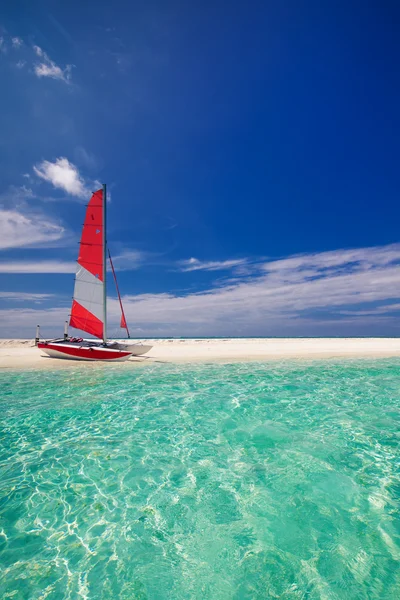 带着热带岛屿的海滩上红帆帆船 — 图库照片