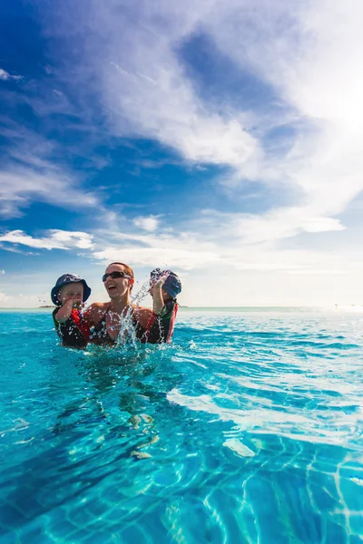 Familia feliz salpicando en la piscina azul de un resor tropical — Foto de Stock