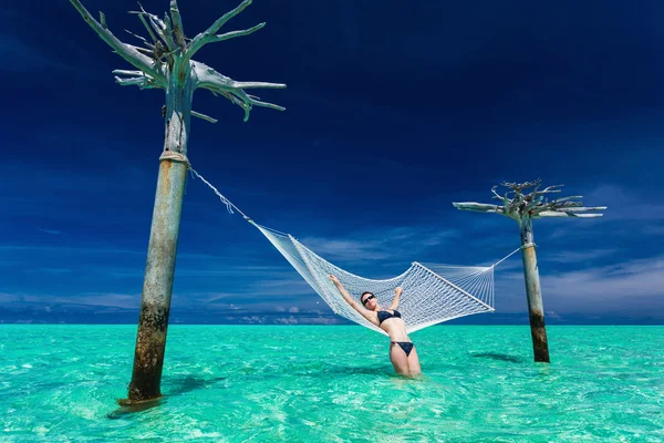 女人在热带环礁湖的水上吊床上放松 — 图库照片