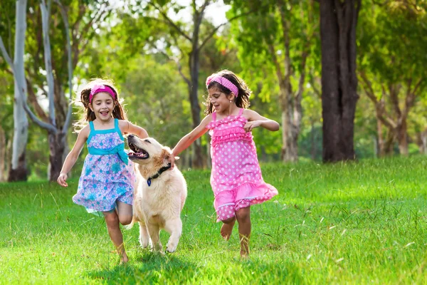 Meninas correndo com um golden retriever — Fotografia de Stock