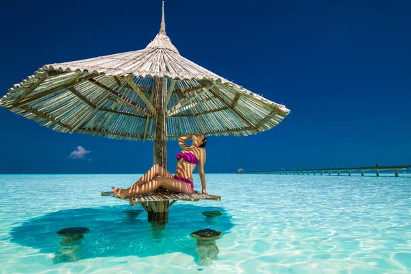 Kvinna i bikini under parasoll i havet — Stockfoto