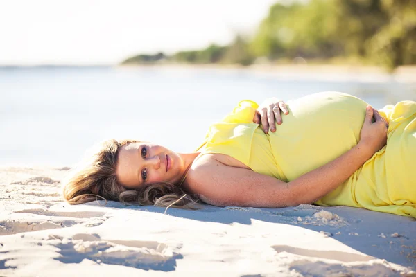 Mulher grávida deitada na praia — Fotografia de Stock