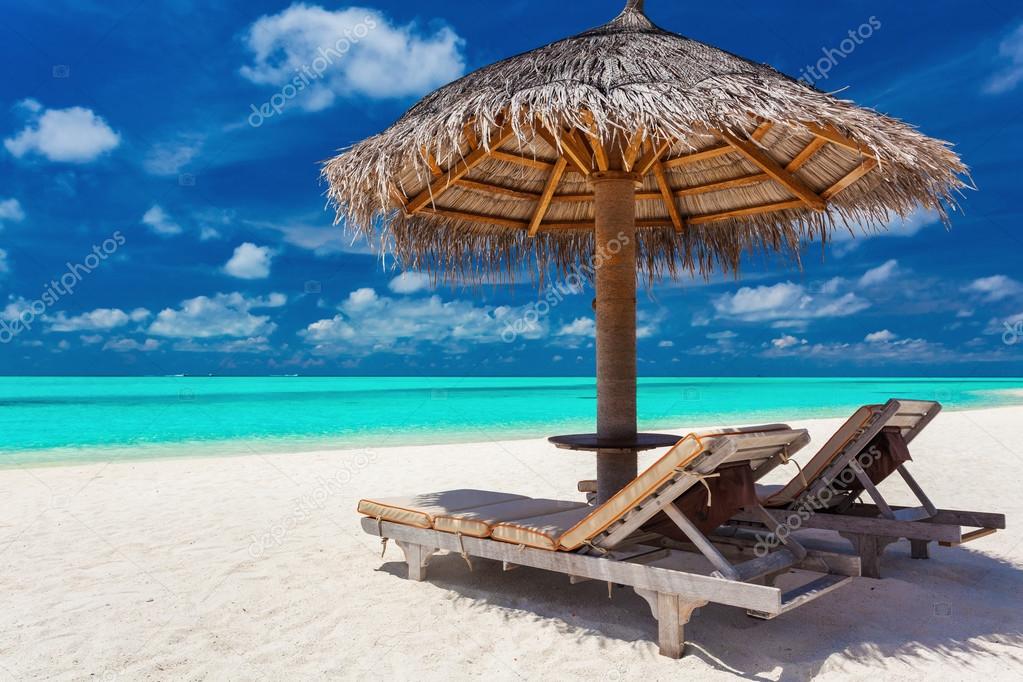 Two chairs and umbrella on a tropical beach Stock Photo by