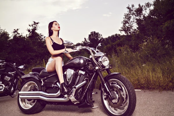 Bela jovem mulher posando com uma motocicleta — Fotografia de Stock