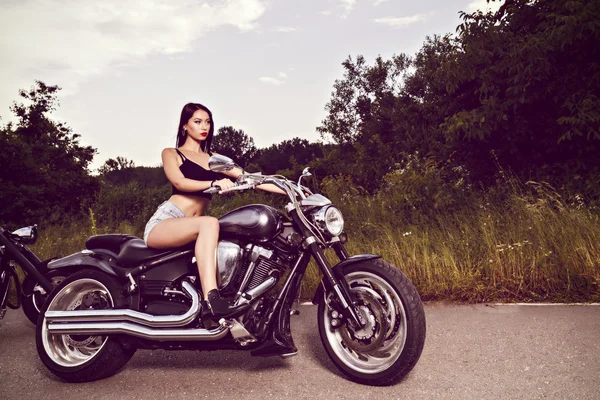 Schöne junge Frau posiert mit einem Motorrad — Stockfoto