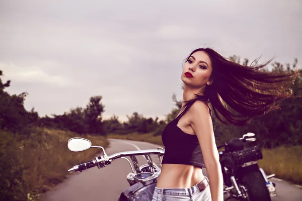 Bela jovem mulher posando com uma motocicleta — Fotografia de Stock