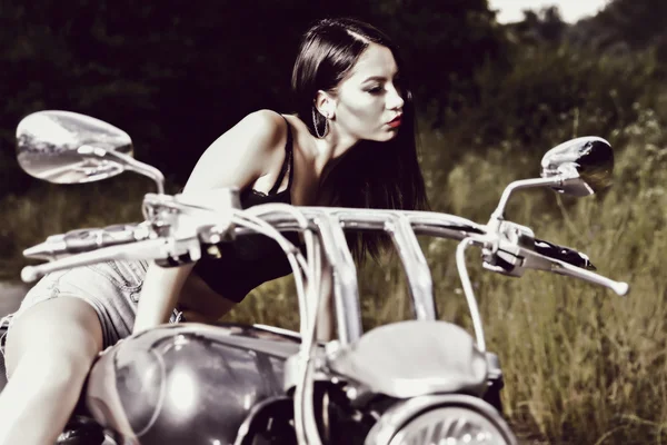 Bela jovem mulher posando com uma motocicleta — Fotografia de Stock