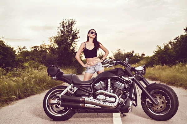 Belle jeune femme posant avec une moto — Photo