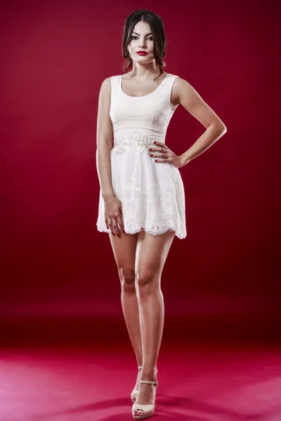 Jovem modelo feminino bonito em vestido branco no fundo vermelho — Fotografia de Stock
