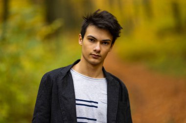 Sonbahar ormanında yakışıklı bir genç adamla portre, moda konsepti..