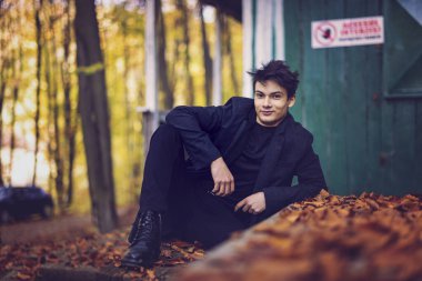 Sonbahar ormanında yakışıklı bir genç adamla portre, moda konsepti..