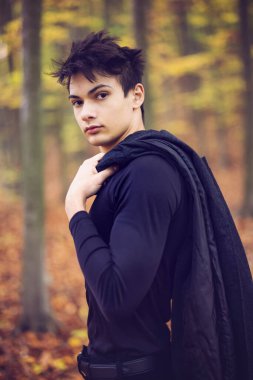 Sonbahar ormanında yakışıklı bir genç adamla portre, moda konsepti..