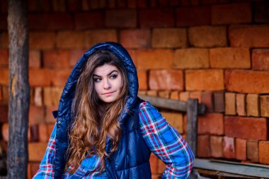 Eski kırmızı bir duvarın arkasında poz veren kız.