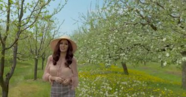 Bahar elması bahçesinde doğanın tadını çıkaran güzel genç bir kadın çiçek açan ağaçları olan mutlu, güzel bir kız..